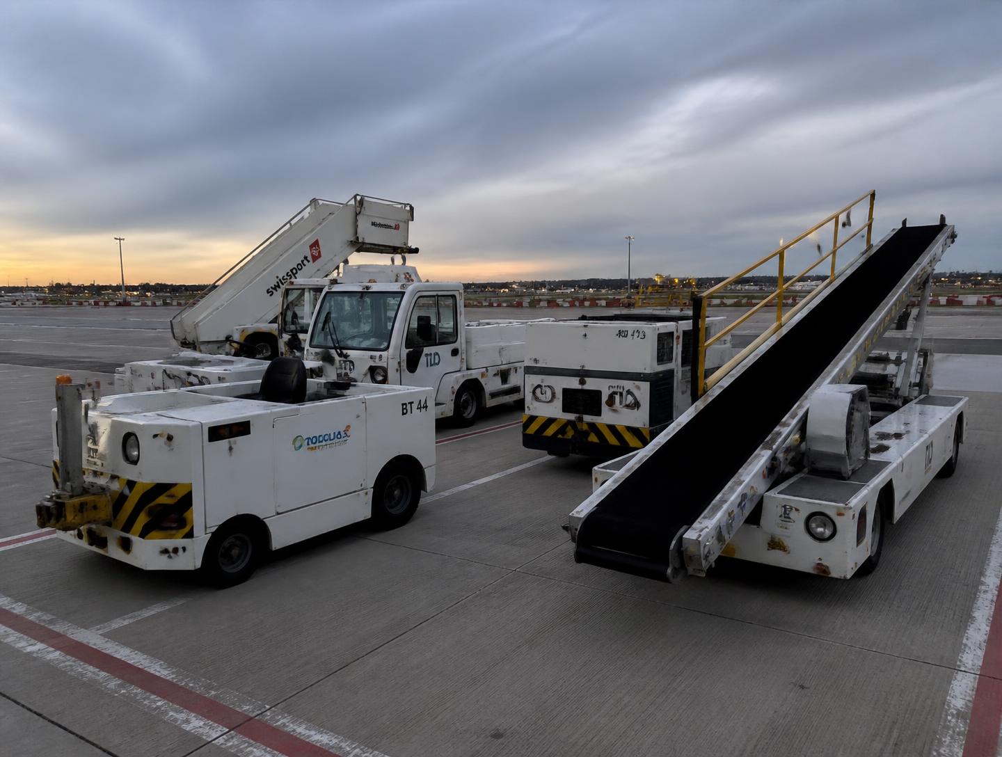 Ground support equipment parked on an airport apron at dusk